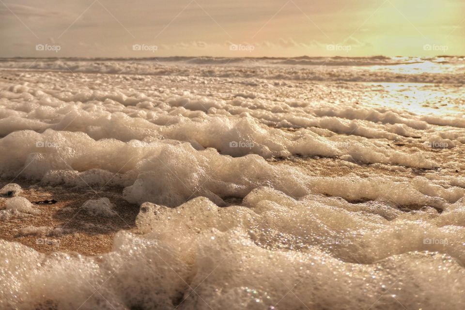 Sunset on a foamy beach