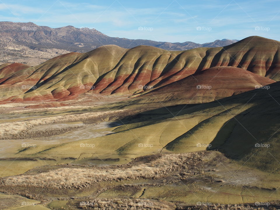 The incredible beauty of the red, gold, and browns of the textured Painted Hills in Eastern Oregon on a bright sunny day.