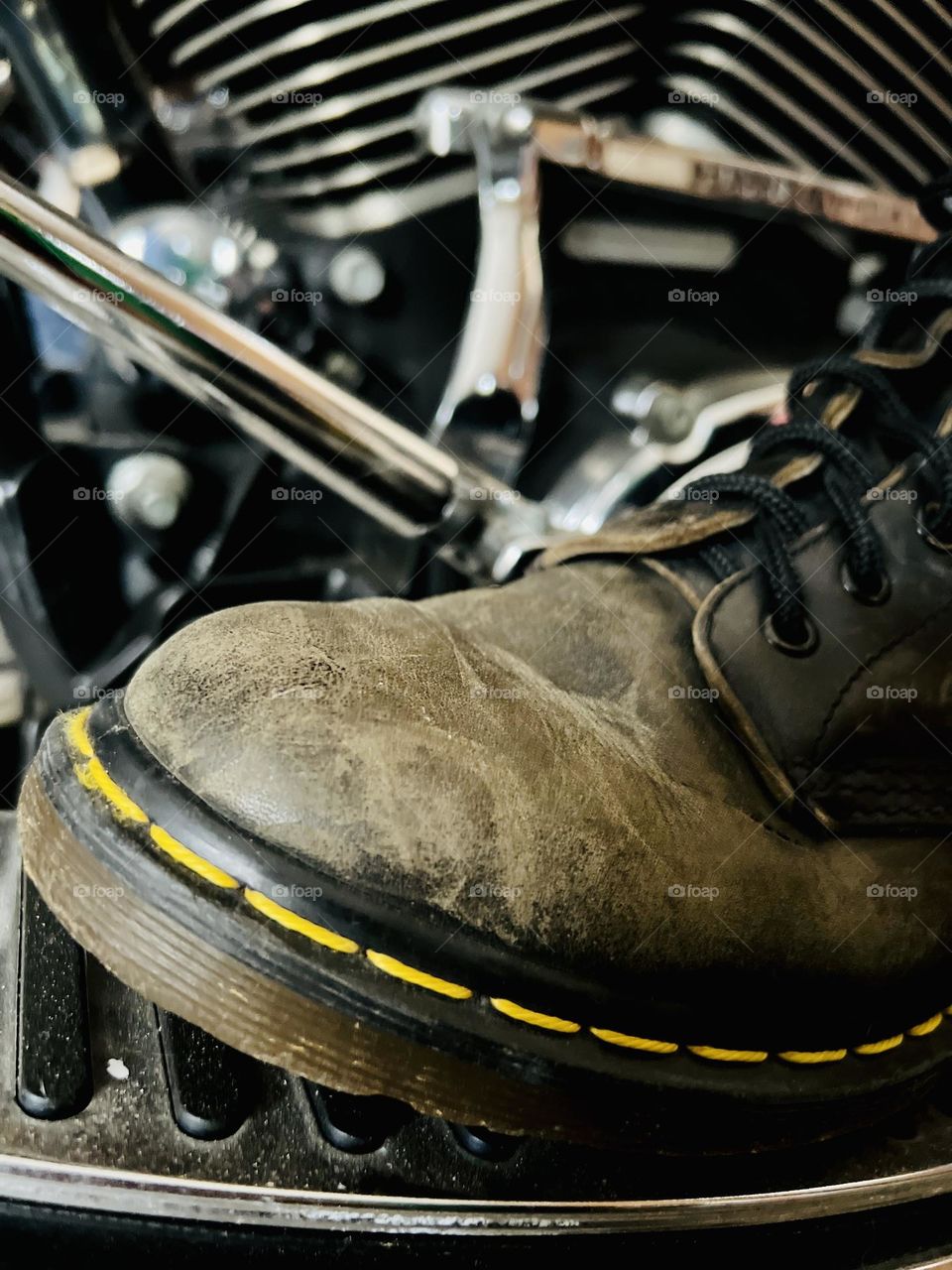 Closeup of worn, older Doc Marten classic boots with motorcycle in background 