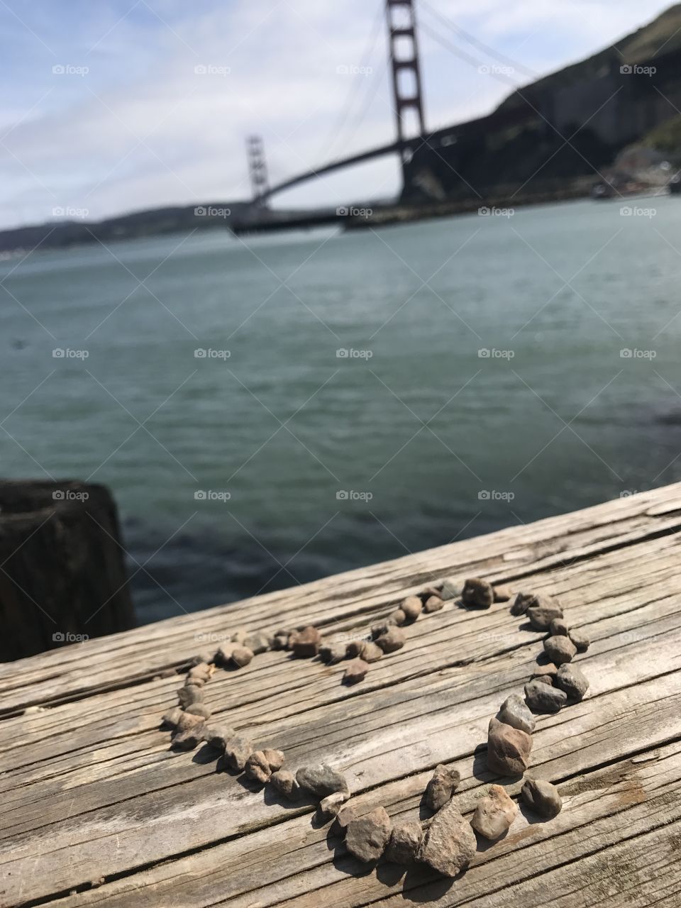 Heart design with pebbles, Golden Gate Bridge in the background in San Francisco California 