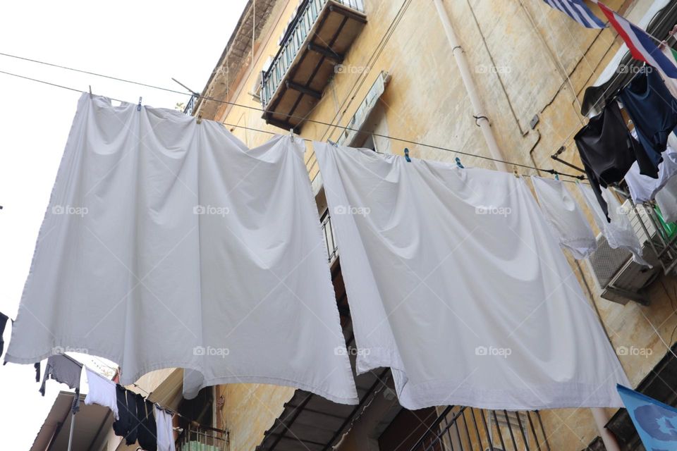White sheets drying between the buildings at the city