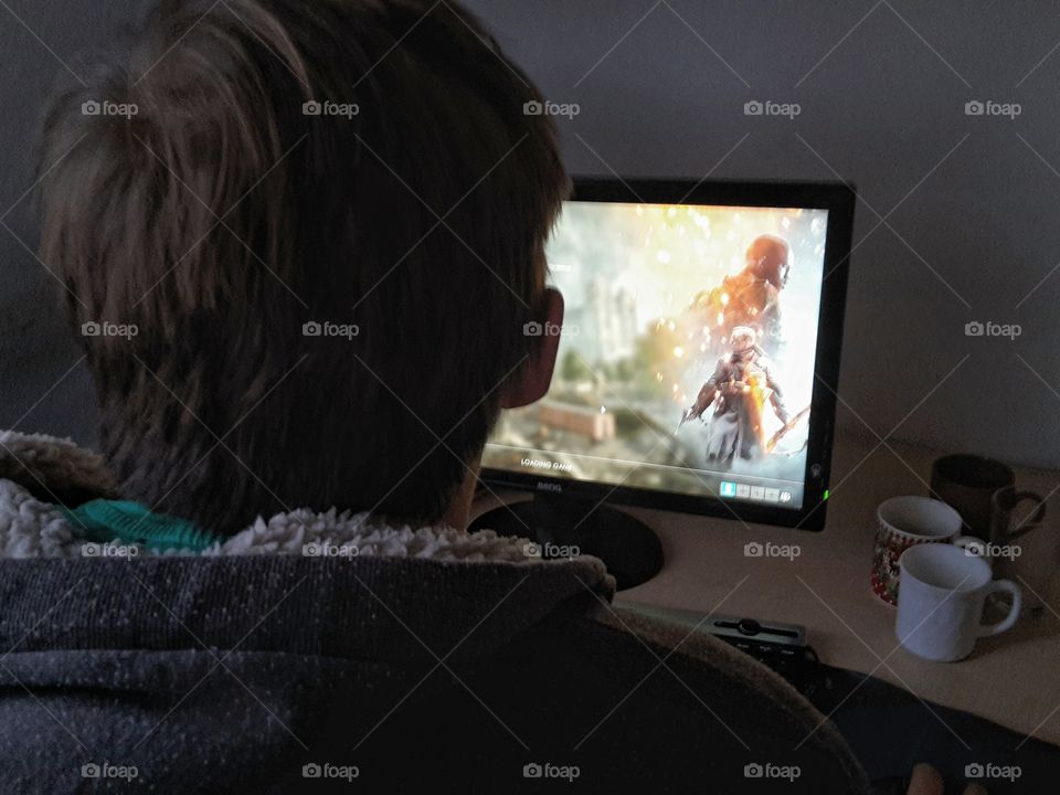 young man playing a shooter game on the computer
