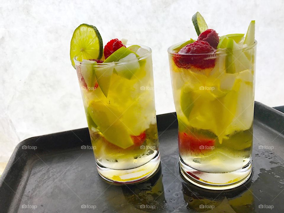 Two wine cocktails with apples and raspberries