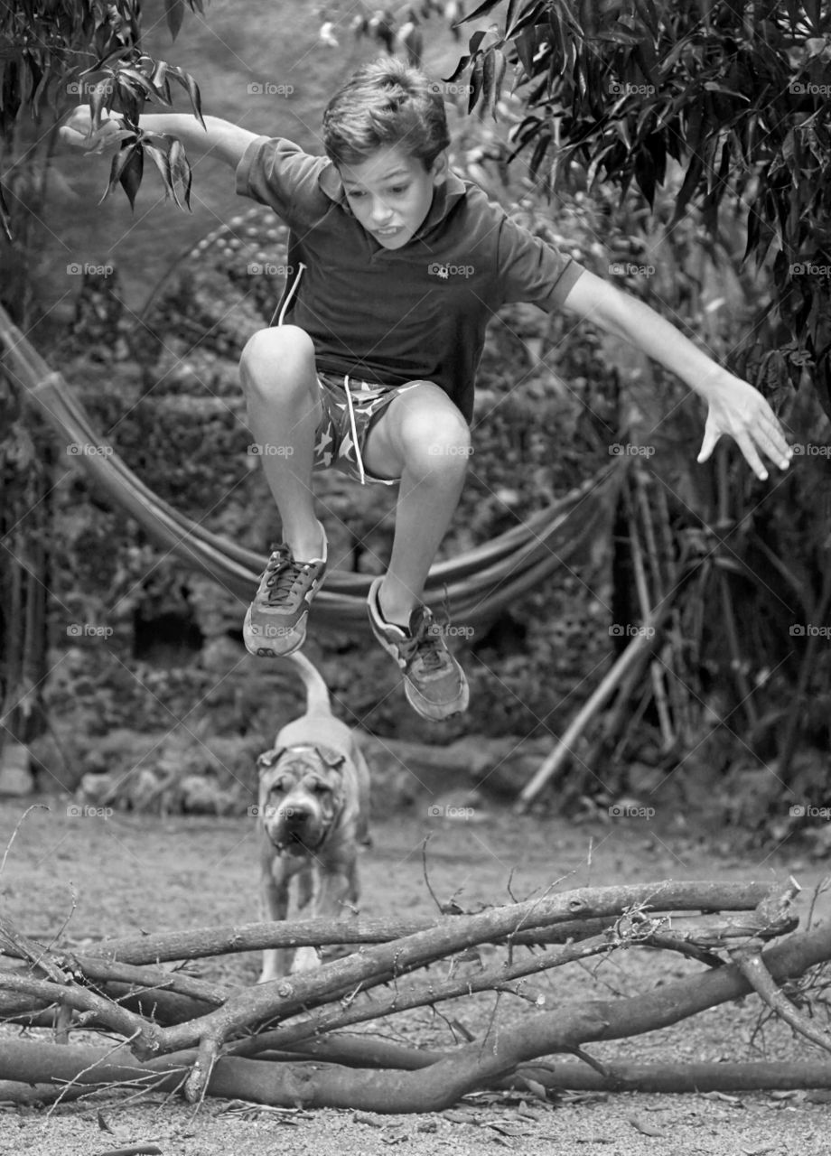 Boy jumping over the tree branch