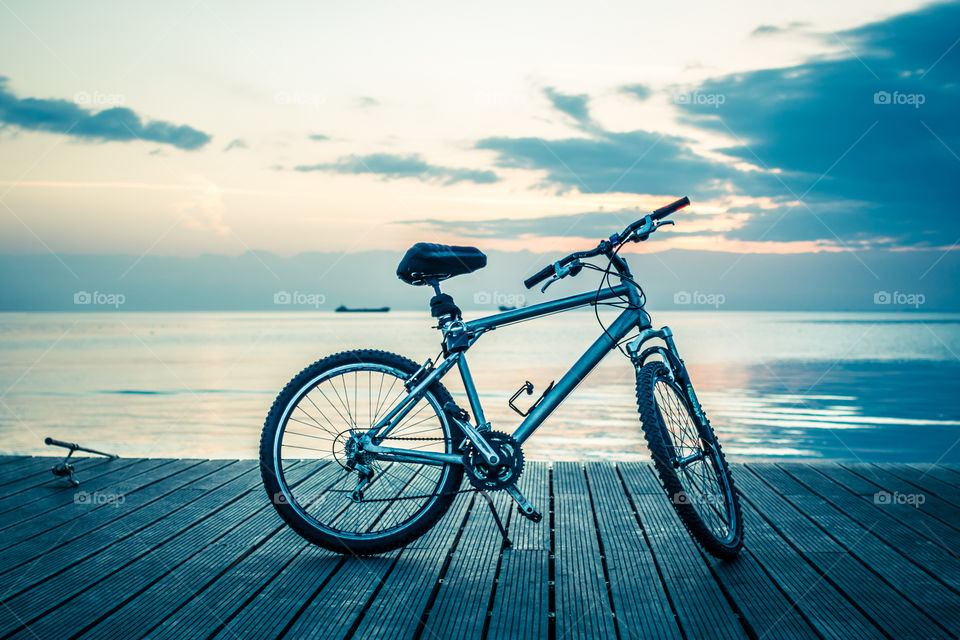 Silver And Black Hardtail Bicycle Parked On Wooden Boardwalk Under White And Blue Cloudy Sky During Dawn
