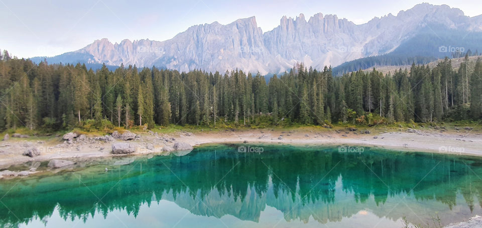 Mountains and forest reflecting in lago di Carezza in Dolomites