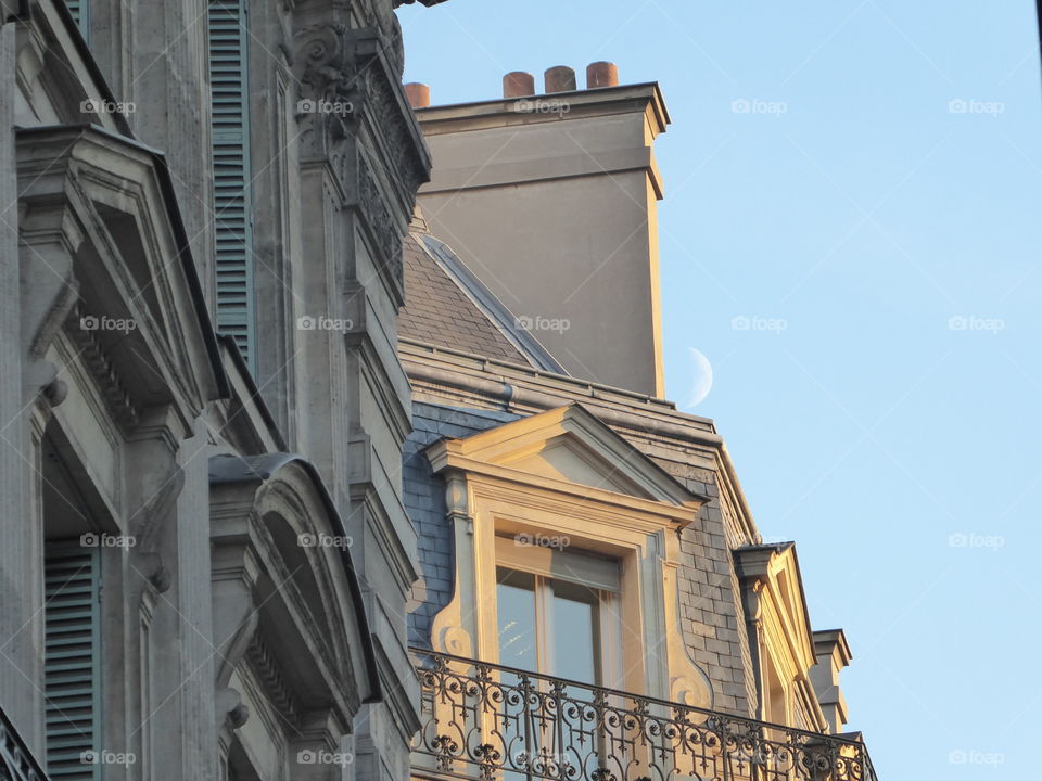 Buildings on Avenue de l'opéra  (Paris) with the moon, on a winter day