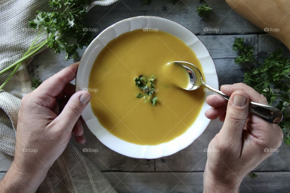 Man eating butternut squash soup with fresh parsley as part of healthy daily routine