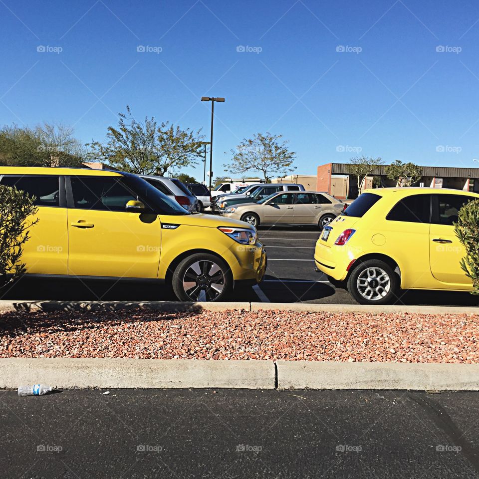 Two yellow cars at a parking lot