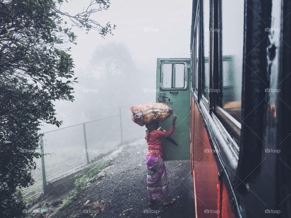 A women boarding a bus with the goods carrying on her head, to sell them in the neighbouring town 