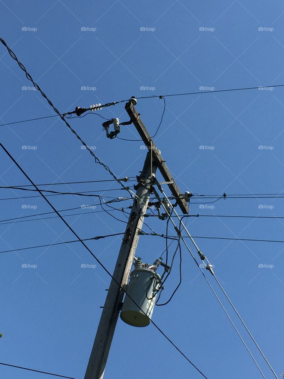 Power lines, telephone pole and transformer on clear blue sky background. 