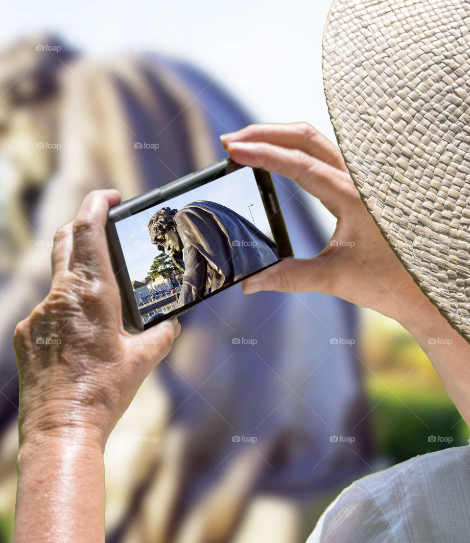 An old woman photographing the statue