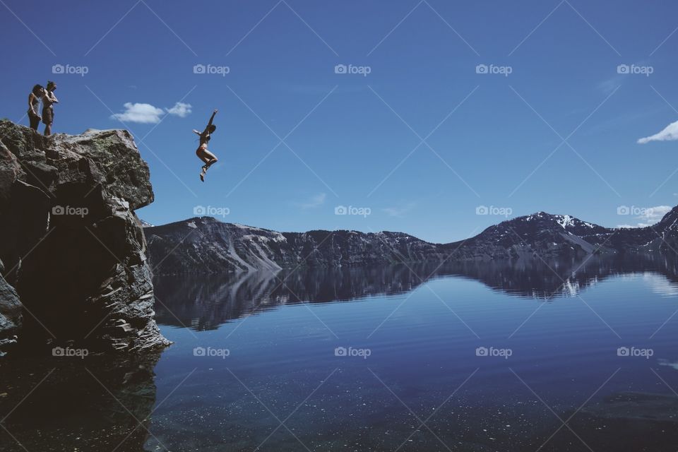 A woman jumping from the rock in the lake
