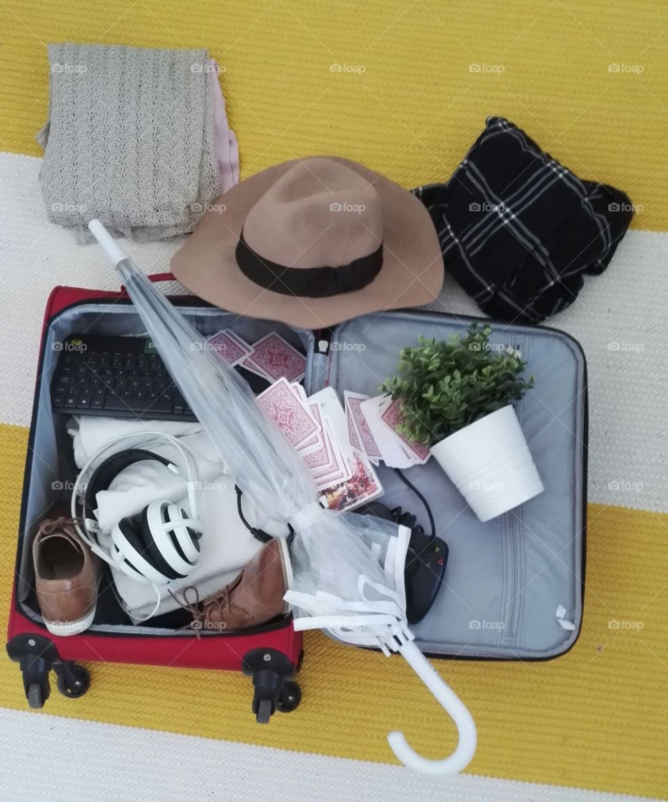 Packing for a vacation. Hat, headphones, umbrella, plant, playing cards, brown shoes.