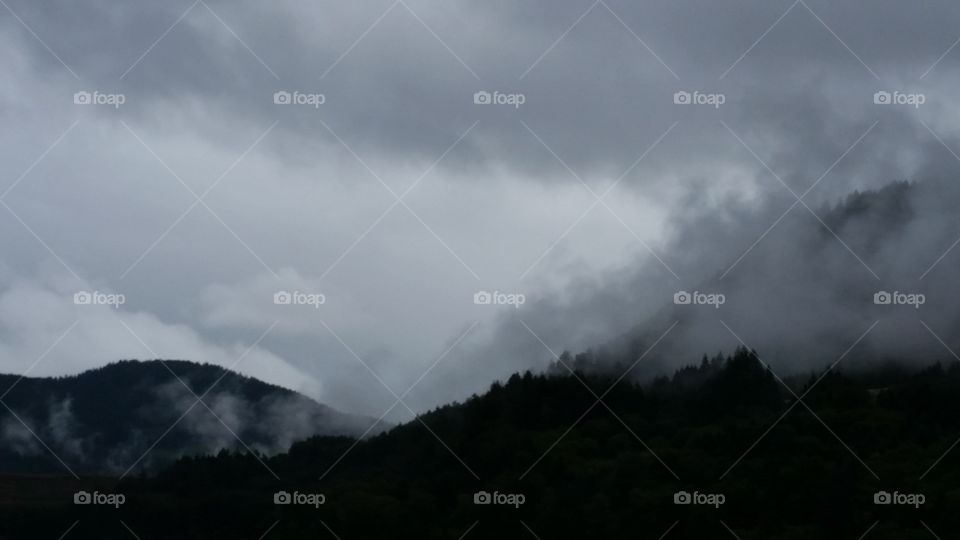 high contrast dark hills topped in low clouds like fog