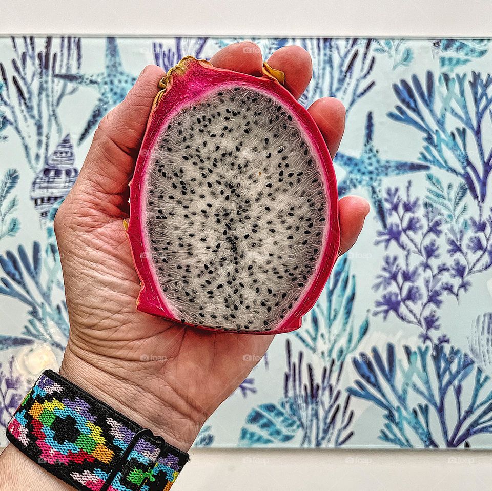 Woman’s hand holds brightly colored dragon fruit, colorful fruits and vegetables, color explosion in nature, making a colorful snack