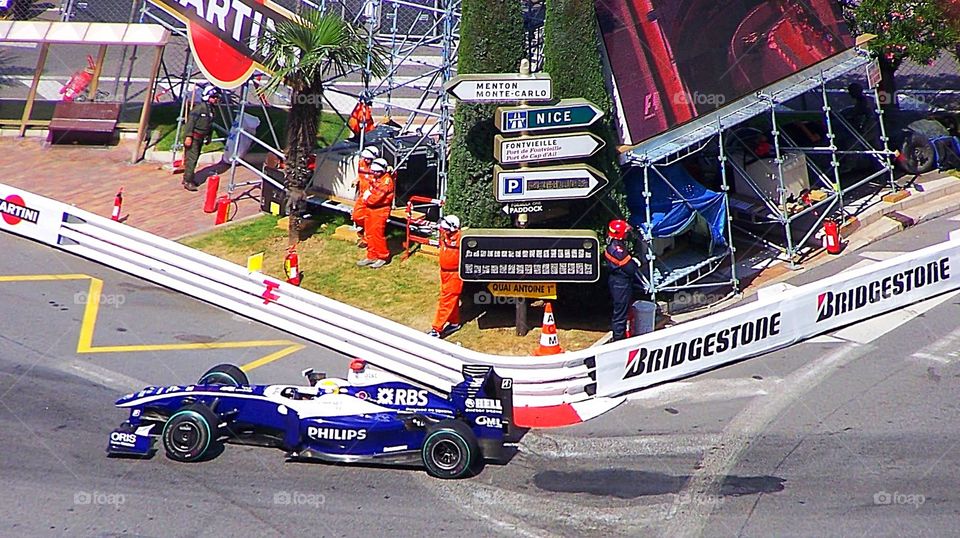 Race car rounding the bend at the World Grand Prix in Monaco; signage (Nice, France) and other regions in the South of France. 