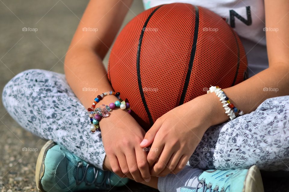 Young girl sitting with a basketball. 