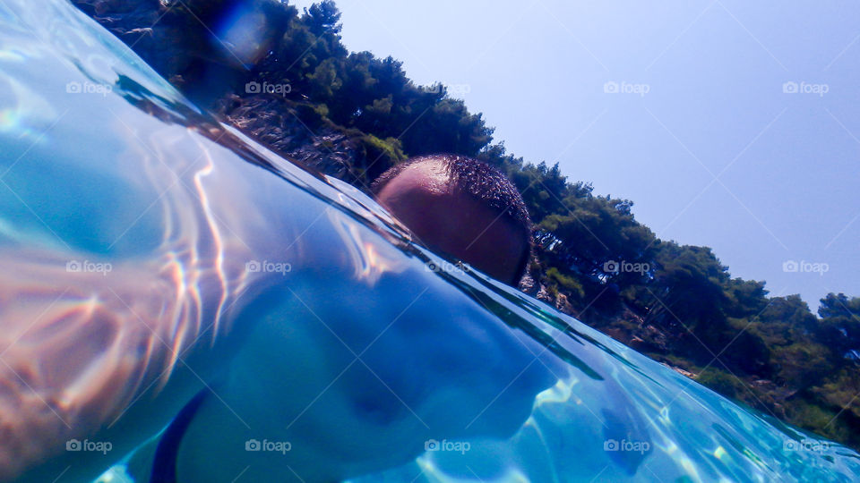 man swimming in the sea with his underwater camera