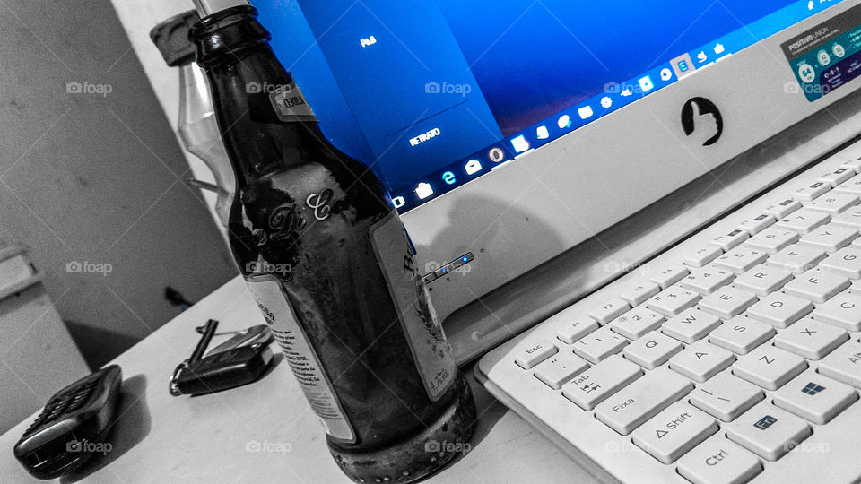 Computador e garrafa de cerveja.