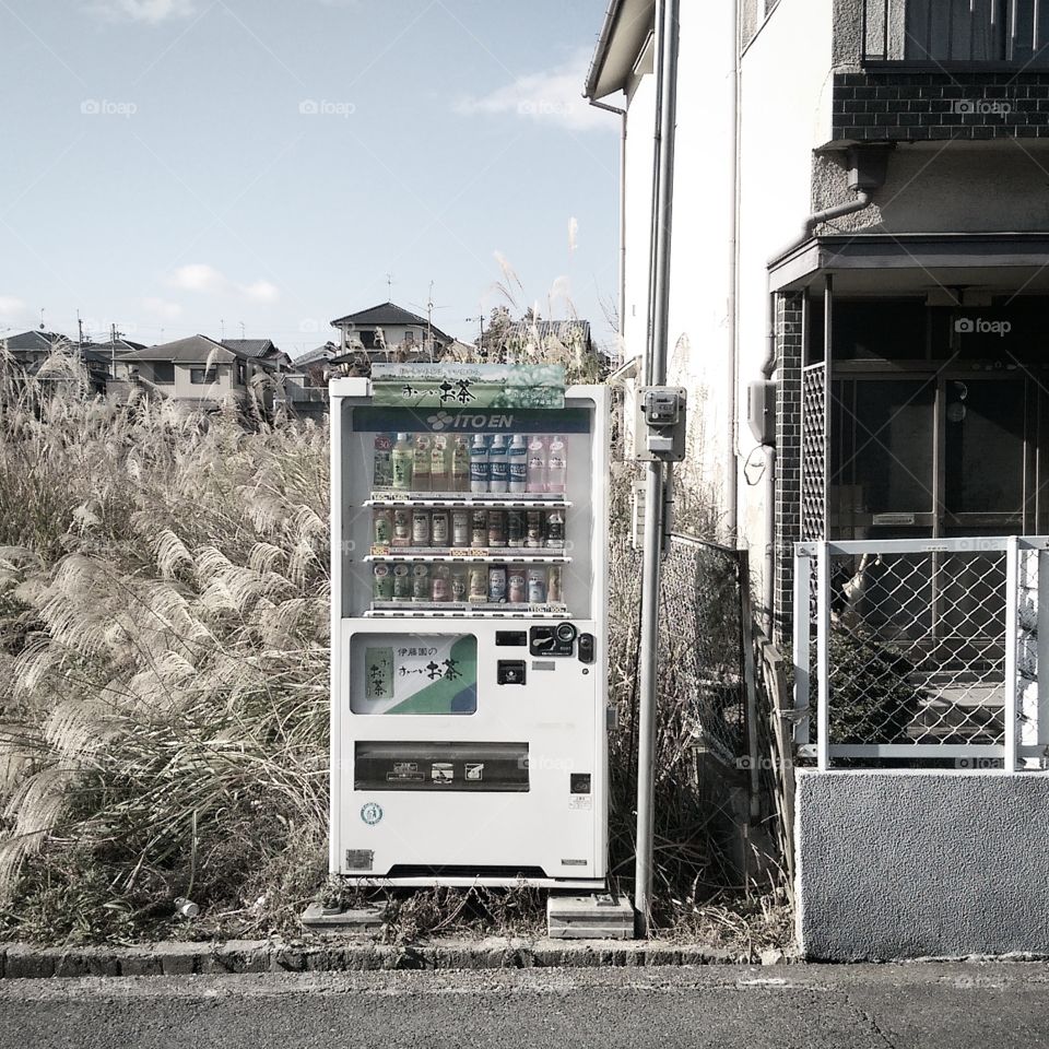 Vending machine in the wild. Japanese love automation and this is fine example. On the side of a street surrounded by weeds and plants. Who run the world? Automated machines.........