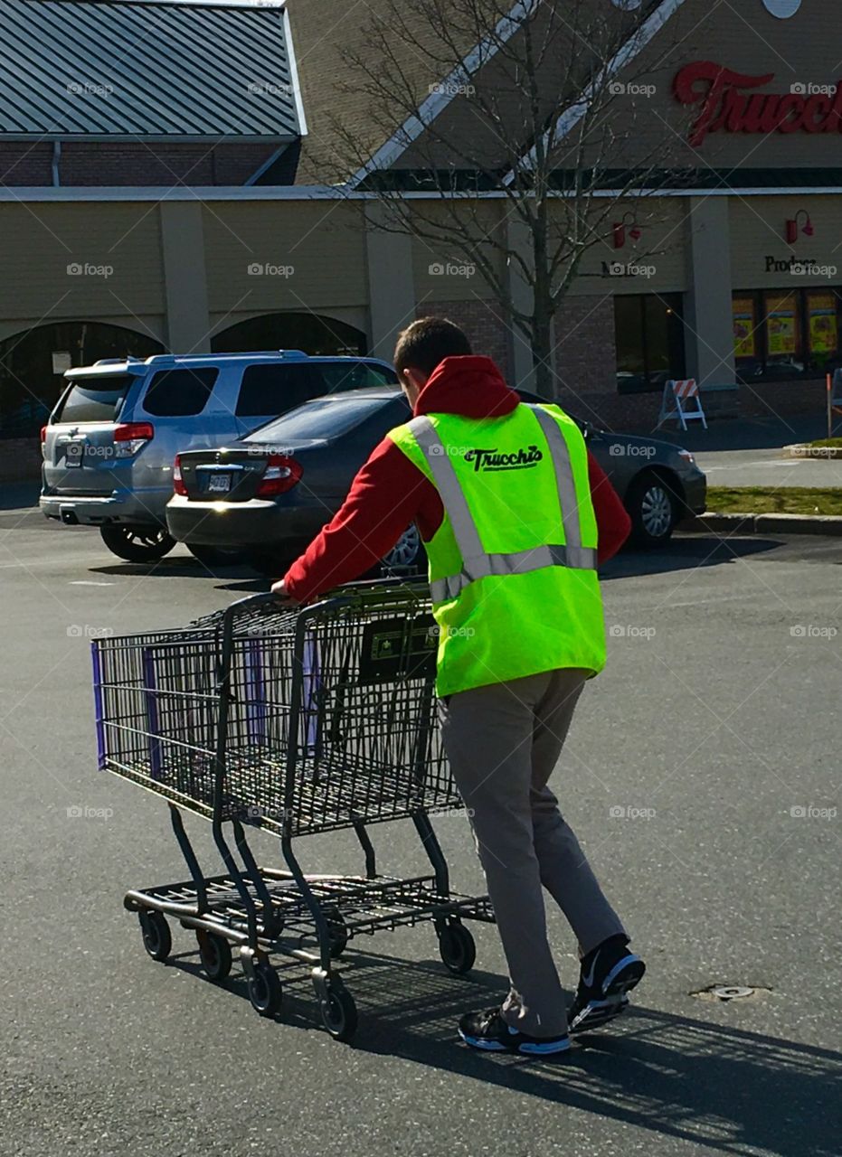Grocery store worker bringing carriages back!

Our grocery store has workers that help to put food bags into the cars. This is great especially if it's bad weather. This man is bringing the carts back into the store after helping someone.