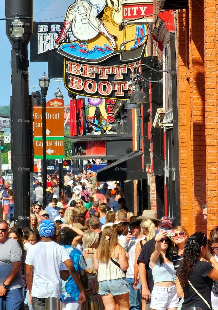 A densely packed street of mostly tourists enjoys a fun afternoon in downtown Nashville