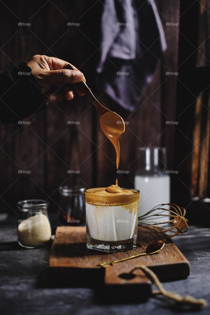 A glass of dalgona coffee iced with dark background.