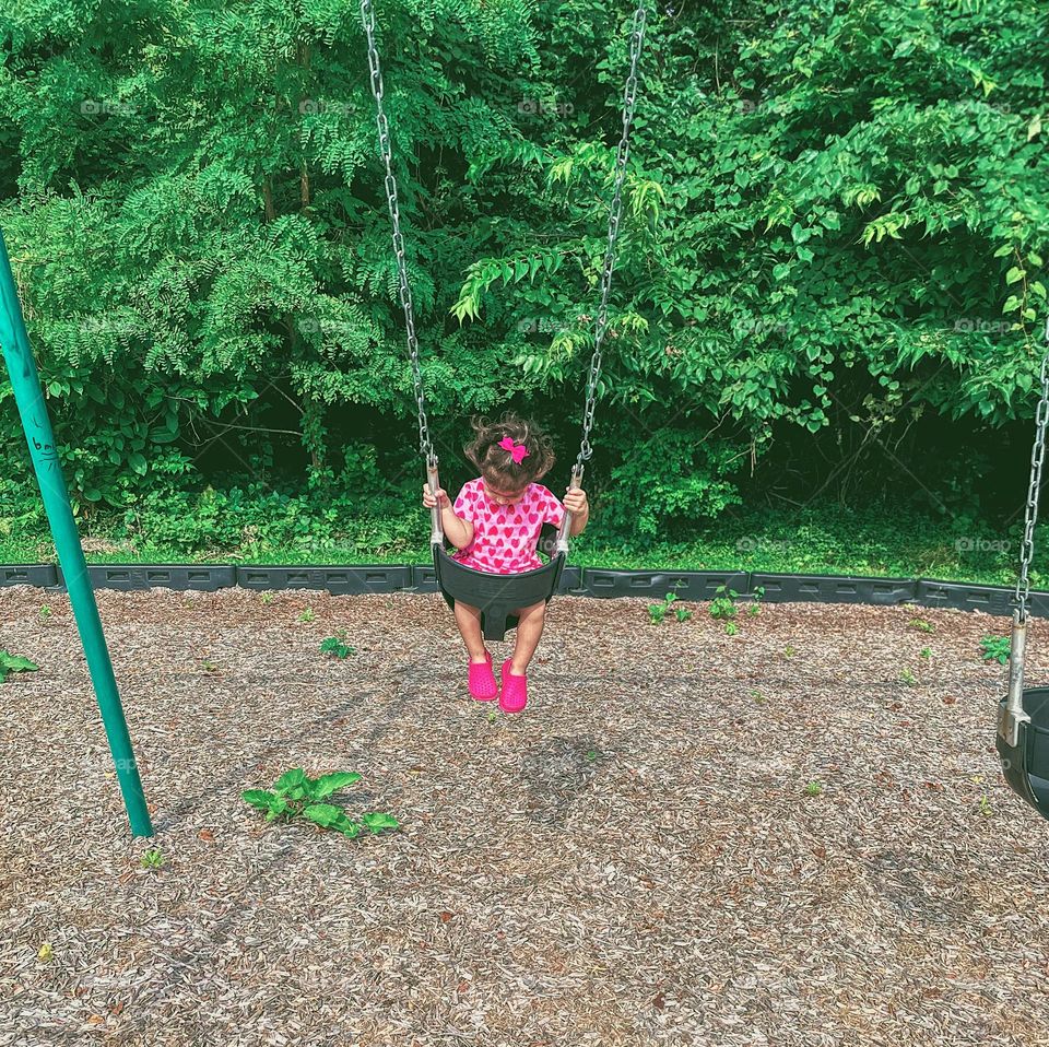 Toddler girl on swing wearing strawberry summer dress, summertime outfits at the park, little girl swinging at the park 