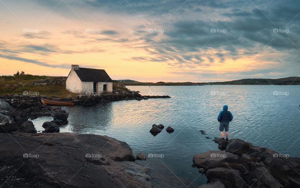 Beautiful lakeside scenic with man on the rock watching sunrise at Screebe fisherman's hut in Connemara National park ,county Galway ,Ireland