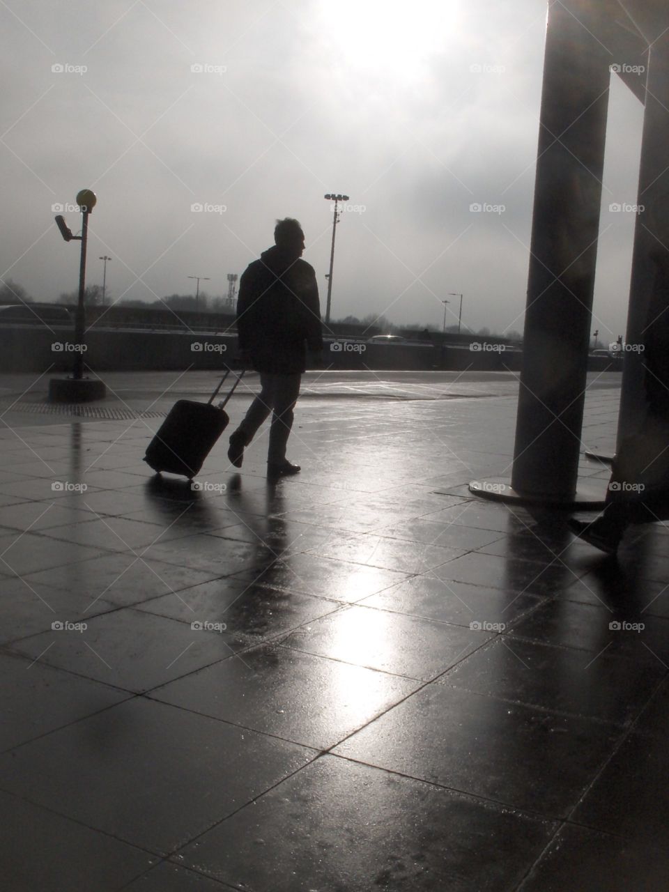 man walking into shiny spot on pavement on rainy day.