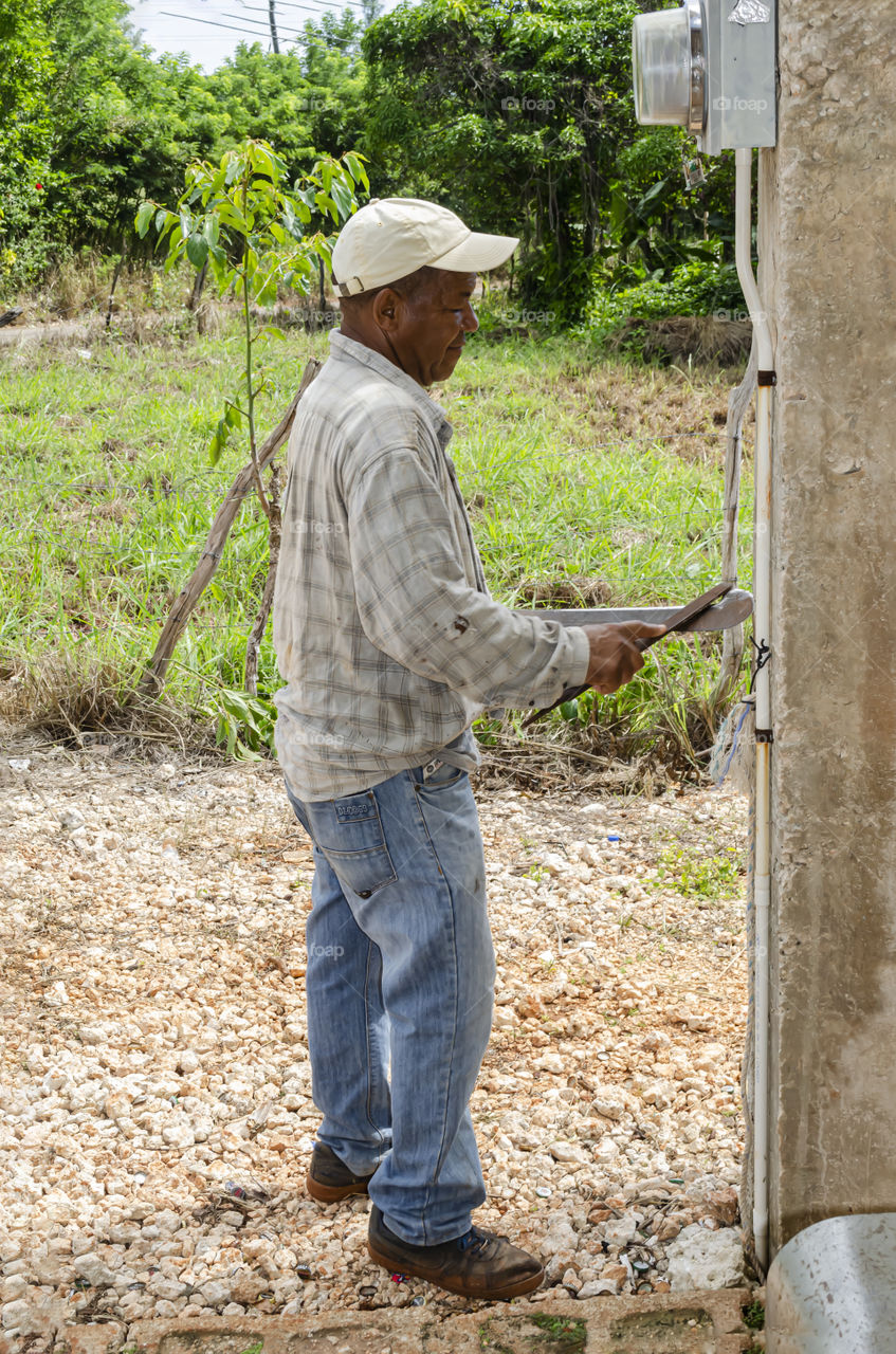 Man Sharpen Machete With Large File (Natural light and camera flash)