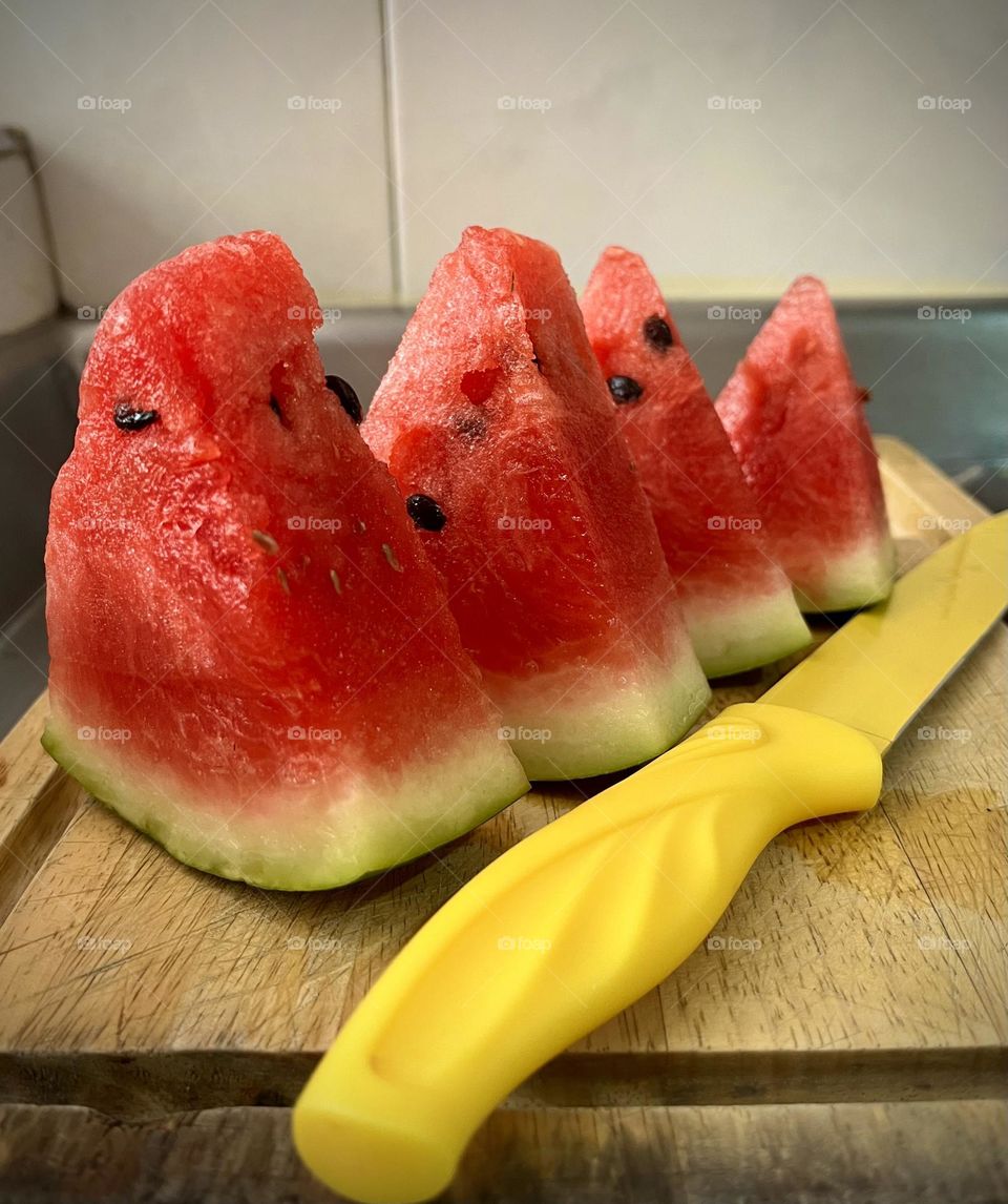 Watermelon slices and a yellow knife in the kitchen 