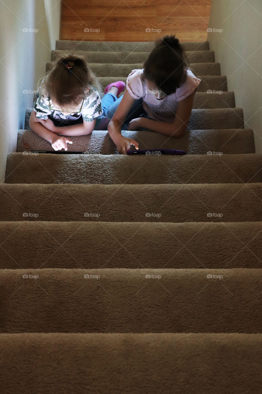 Siblings playing video games on the stairs