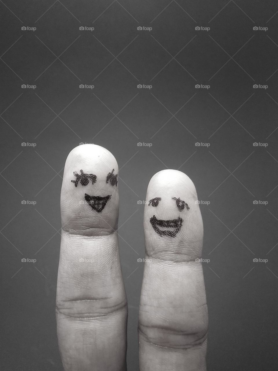 two human fingers drawn to resemble a woman's face and a man's face with a happy expression in the photo in black and white style.