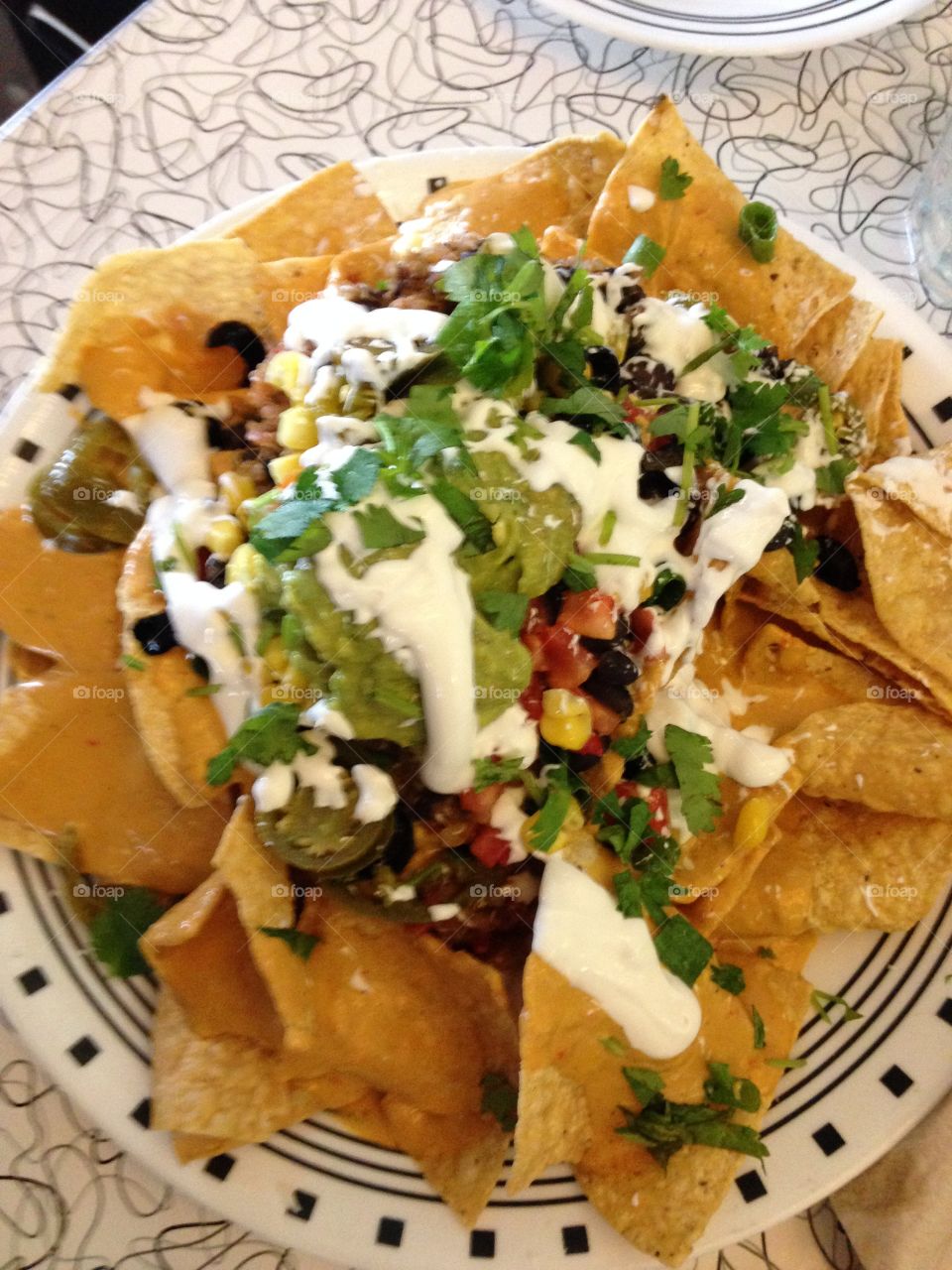 Nacho Supreme - made with our original recipe cashew-based nacho cheese and topped with quinoa, black beans, black olives, cilantro, corn, tomatoes, green onions, sour cream, guacamole & pickled jalapenos. At the Spiral diner in Dallas all vegan