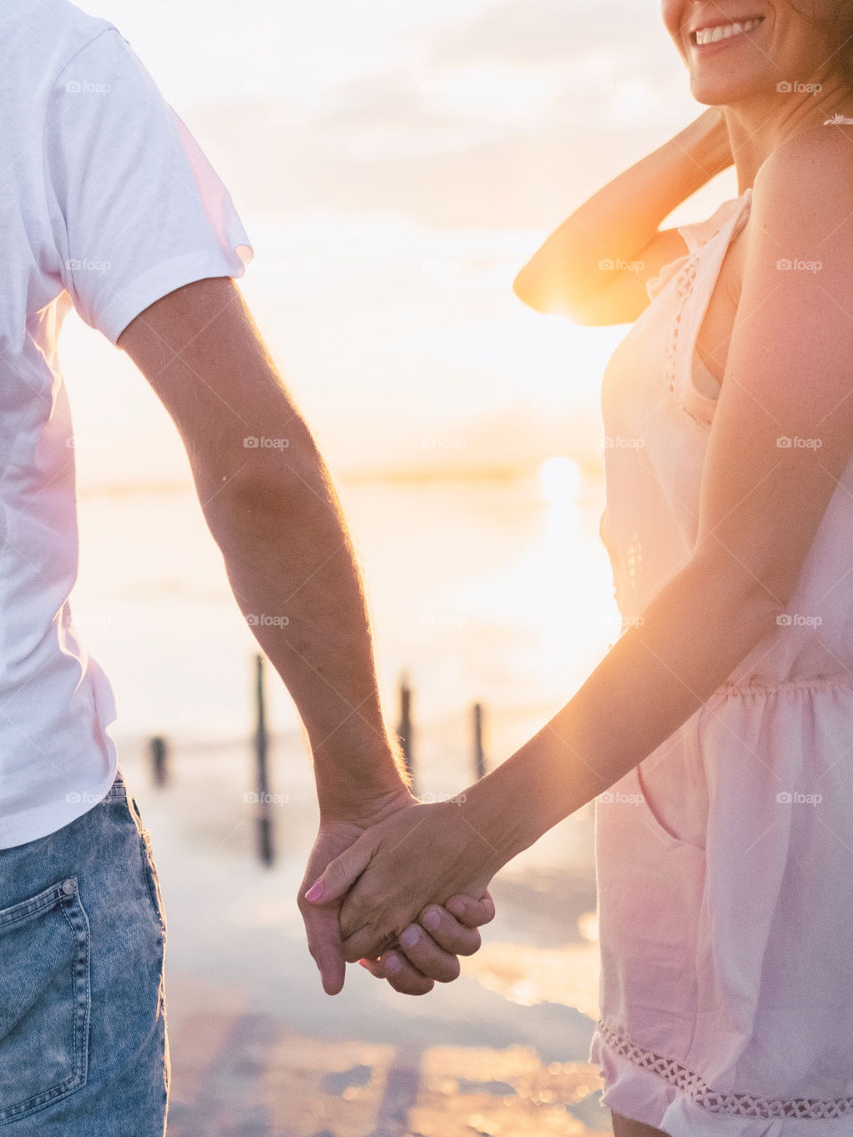 Happy couple is holding hands in the sunset