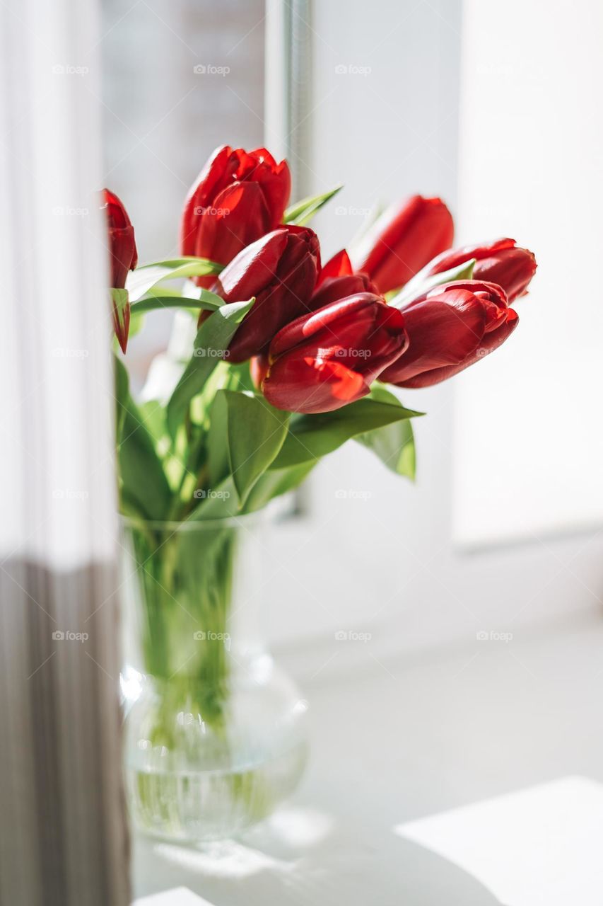 Bouquet of flowers tulips in vase on window sill at home 