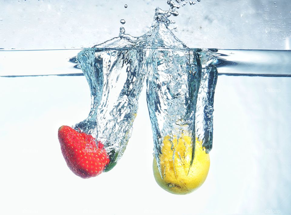 Strawberry and lemon splash down on water