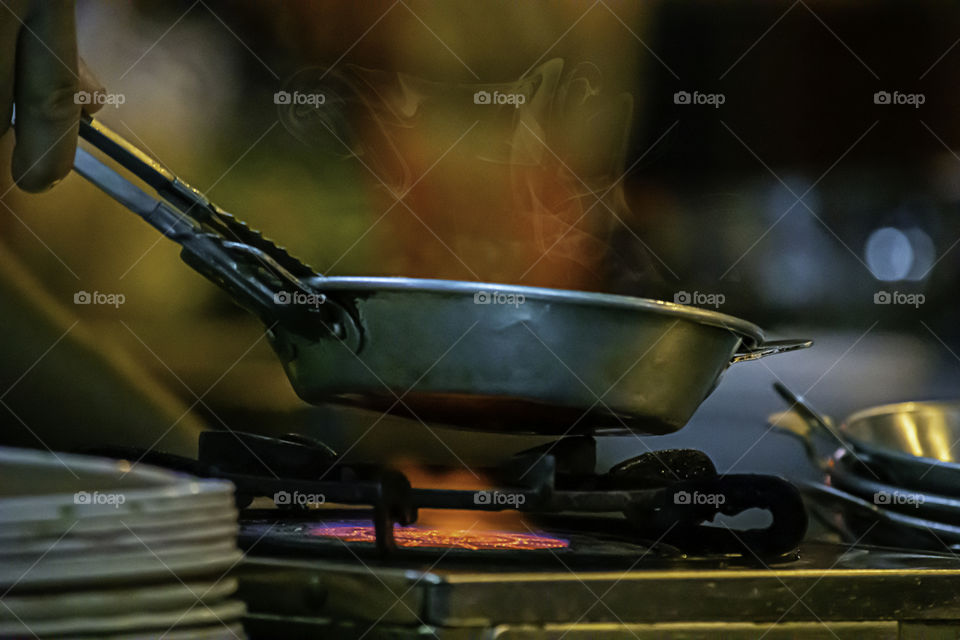 Stainless steel pan on the stove with a yellow flame.