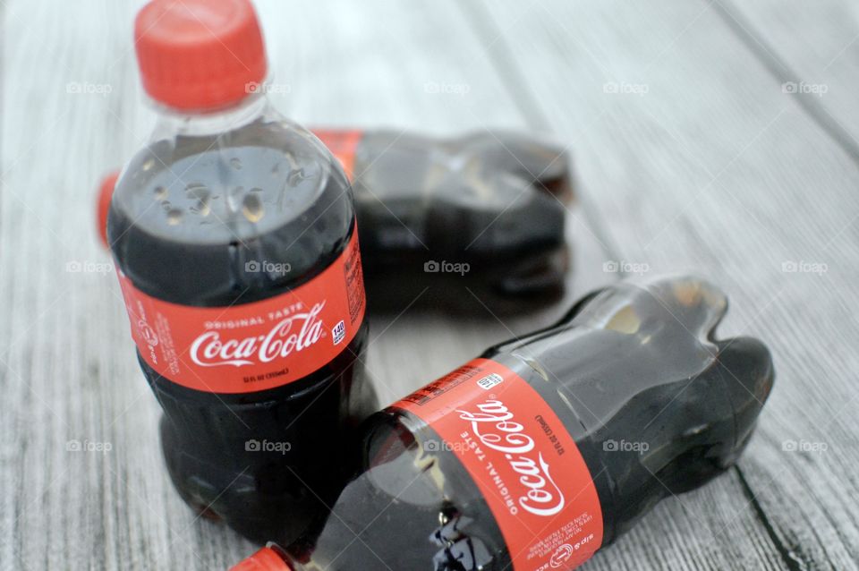 Three plastic bottles of Coca-Cola on a white rustic background