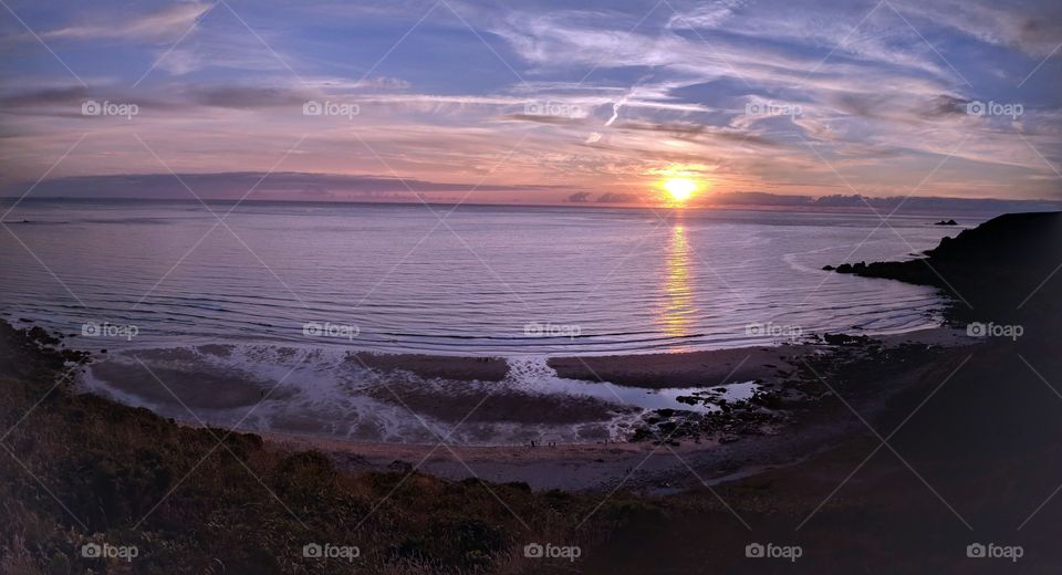 A lovely sunset at gwenver beach in Cornwall. Peaceful and calming panorama with waves crashing in the foreground.