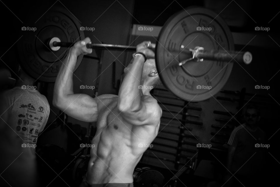 Muscular man lifting weight in gym