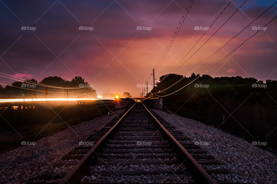 A colorful sunset above train tracks with lens flare.