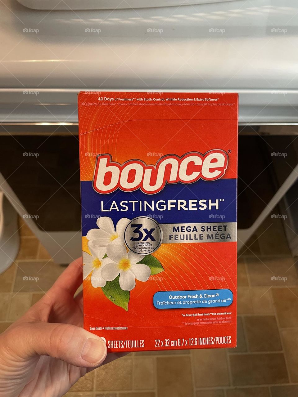 Woman’s hand holding Bounce dryer sheets, doing laundry at home drying clothes at home, using Bounce dryer sheets at home, preventing static cling with Bounce dryer sheets