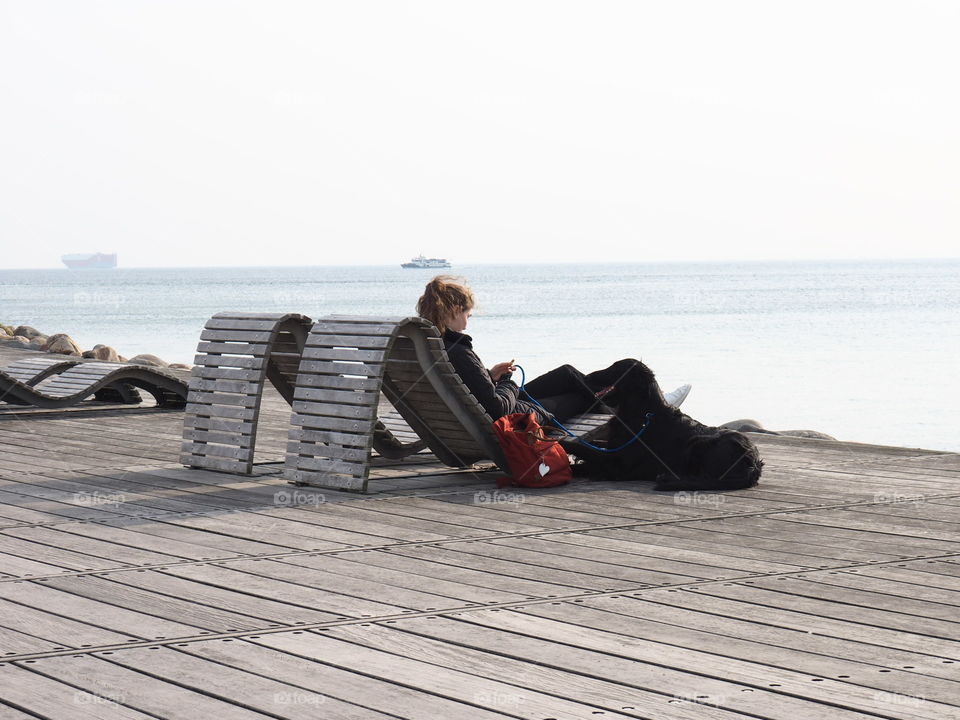 Girl with black dog on a sunny day at the coast in Helsingborg, Sweden.