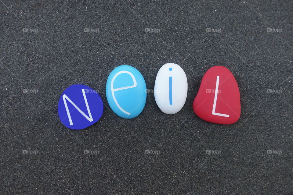 Neil, masculine given name composed with multi colored stones over black volcanic sand