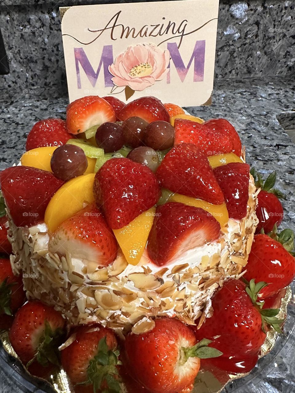 Happy Mother’s Day - A Mother’s Day delight. A delicious, colorful Strawberry Peach Sensation Cake. It is decorated with fresh strawberries, peaches, and grapes, and has sliced almonds around the sides.