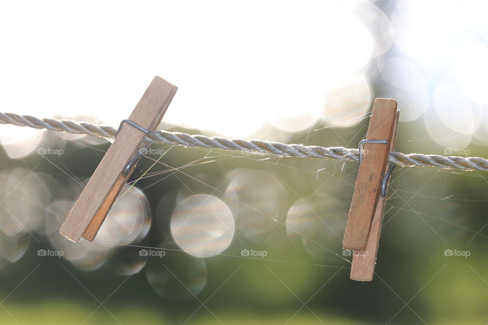 Fragility Imagery; two wood clothes pegs clothespins in white rope line, closeup Bokeh 