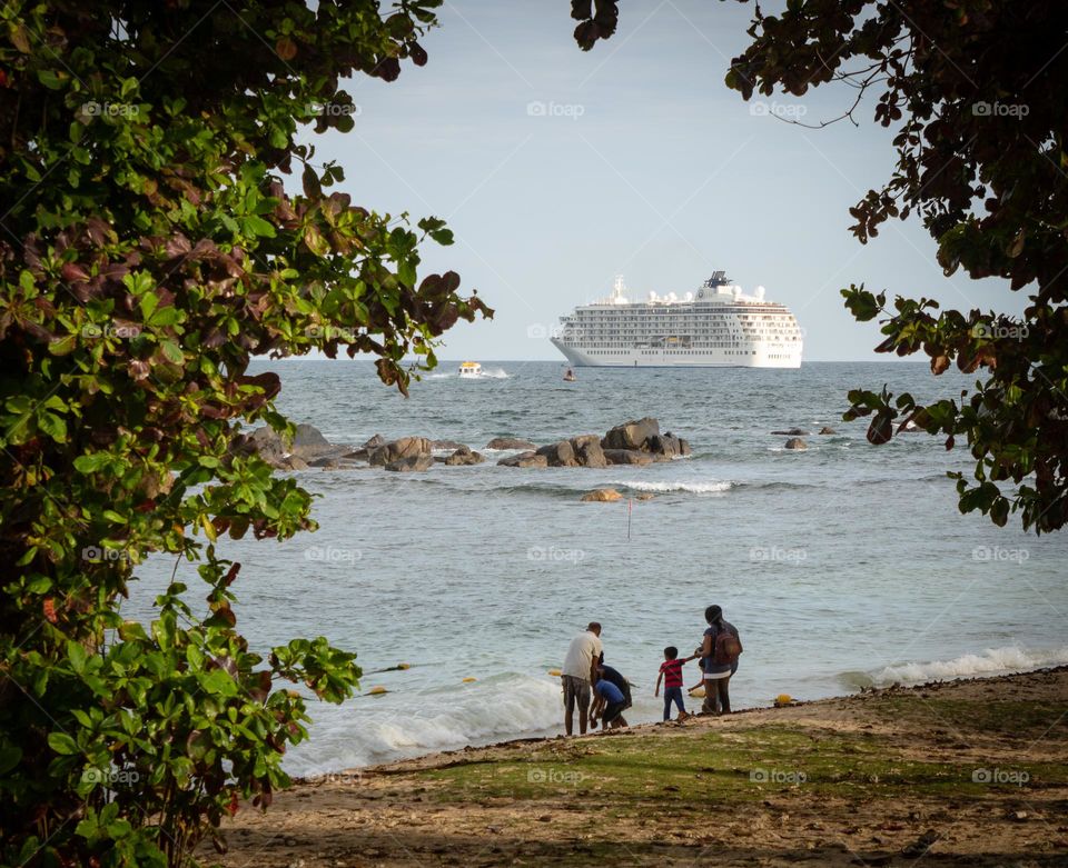 Passenger ship parked in the sea and peoples are playing at beach